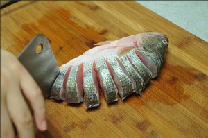 將鱸魚清洗干凈，從脊椎處切斷至腹部，腹部保留1cm左右不要切斷。