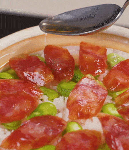 大米出現(xiàn)小孔時(shí)開(kāi)蓋放香腸，往鍋邊淋入少許油，再燜煮8~10分鐘左右。